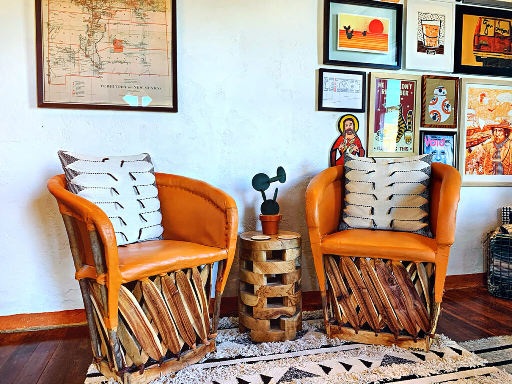 Art wall behind orange traditional Mexican equipale barrel chairs
