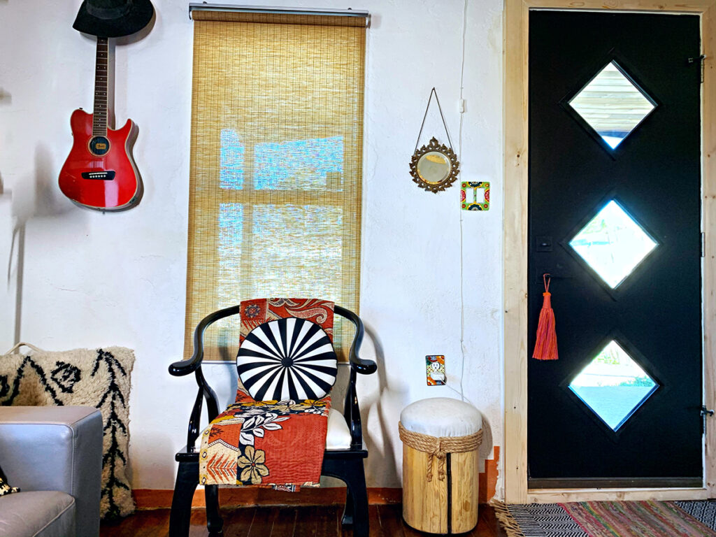 Midcentury front door with vintage black lacquer chair and red electric guitar
