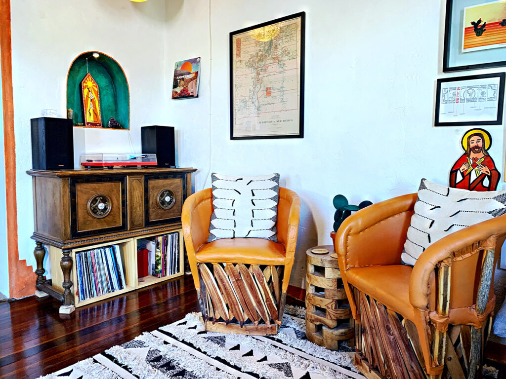 Vinyl record player on vintage buffet with orange traditional Mexican equipale barrel chairs on black and white rug